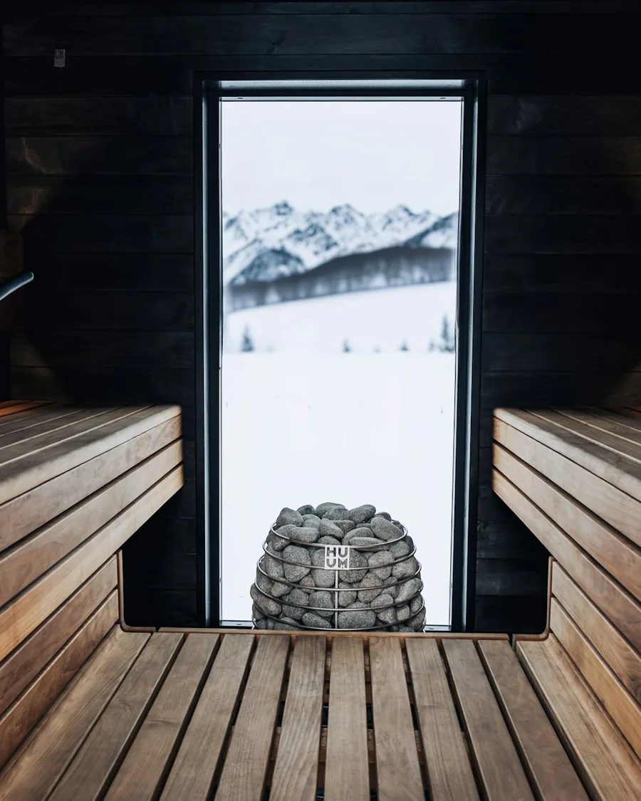 Mörk bastu med stenugn och en öppen dörr mot snö