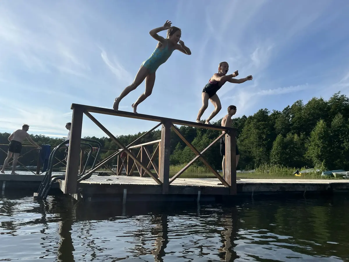 Två personer hoppar från en brygga ut i sjön