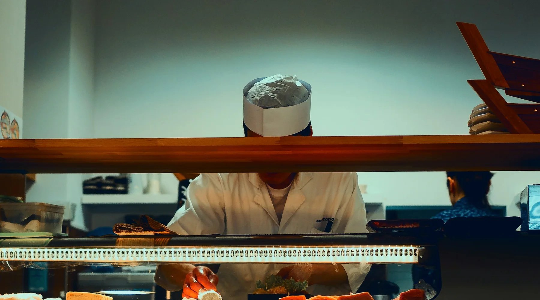 Sushikock bakom en upplyst disk sedd från gästens plats