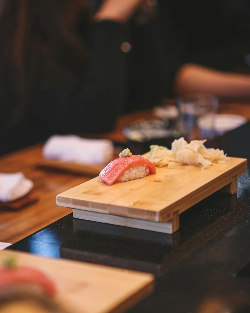 Tonfisknigiri på en träbricka vid en upplyst sushidisk