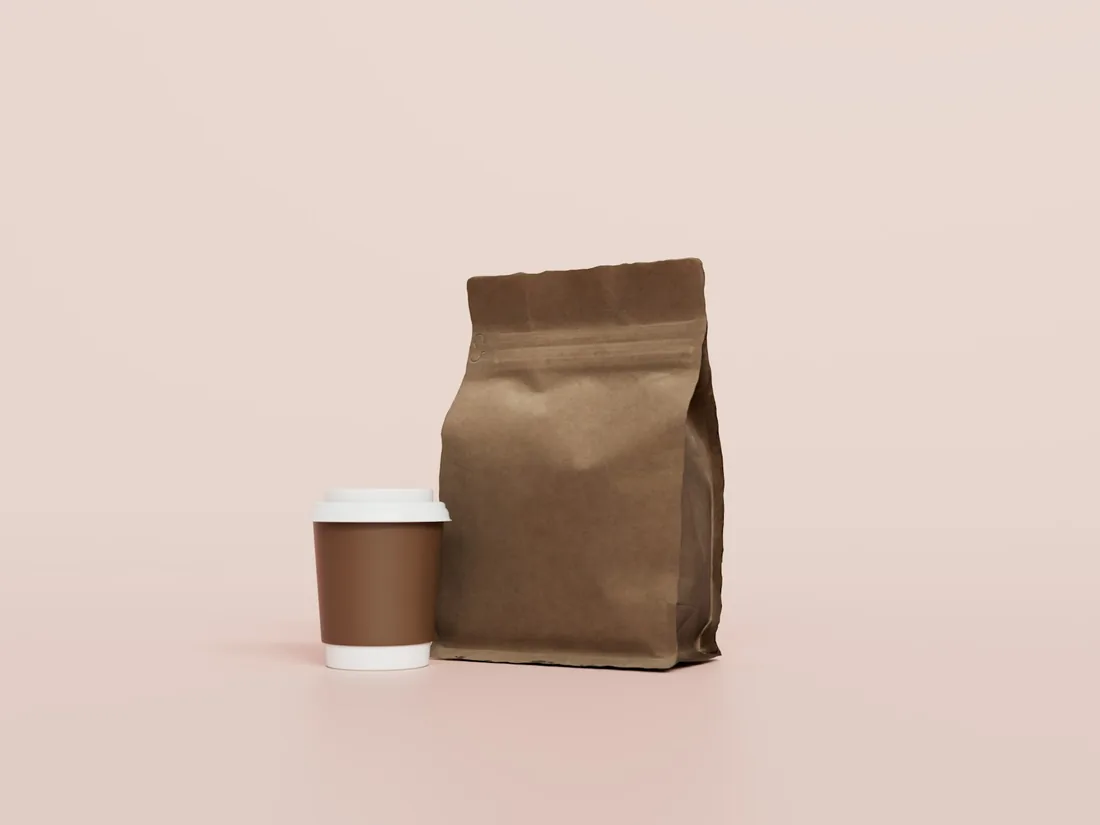 En kaffepåse och en kopp kaffe mot en rosa bakgrund