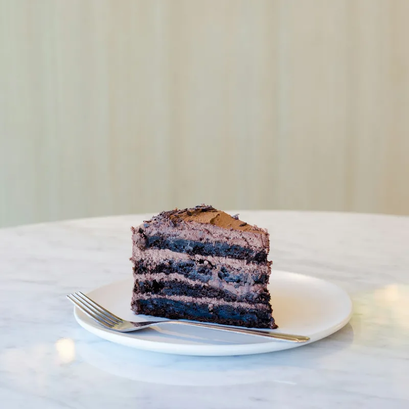 En bit chokladtårta med gaffel på vit tallrik